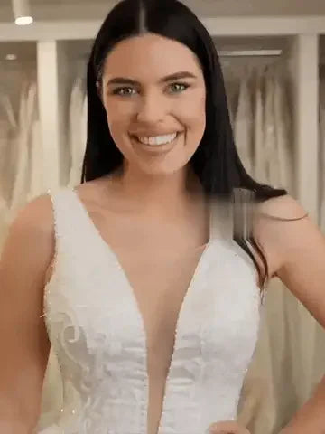 Smiling woman in elegant white dress with plunging neckline, in boutique-fitting room, Formivelle style.