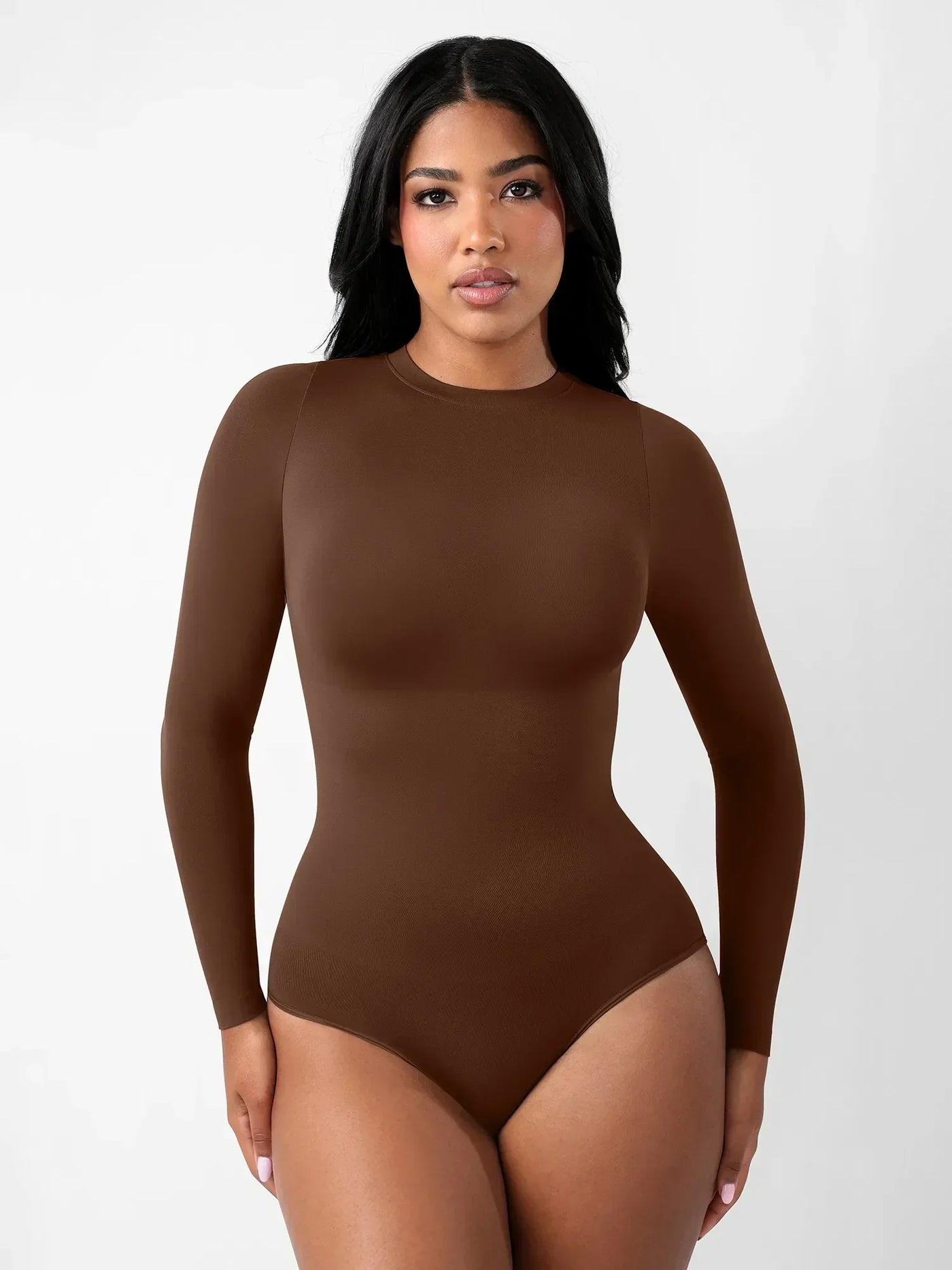 Woman wearing a seamless brown long sleeve crew neck bodysuit by Formivelle against a white background.