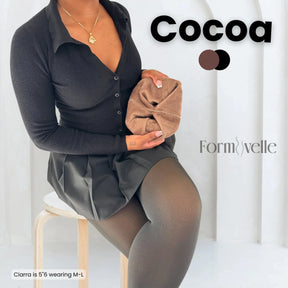 Woman wearing Formivelle cocoa fleece lined tights, holding brown tights, seated in studio setting.