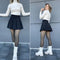 Woman in Formivelle fleece-lined tights, black skirt, white ribbed top, and white boots