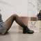 Woman in Formivelle fleece-lined tights, plaid skirt, and boots by shopping bag in boutique