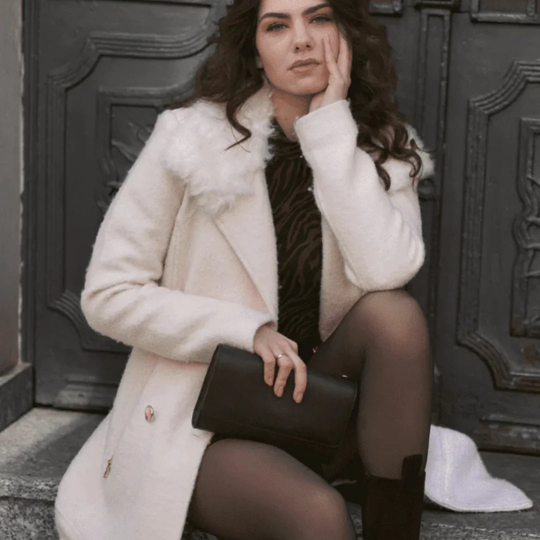 Woman wearing Formivelle fleece-lined tights, white coat, and black clutch sitting outdoors