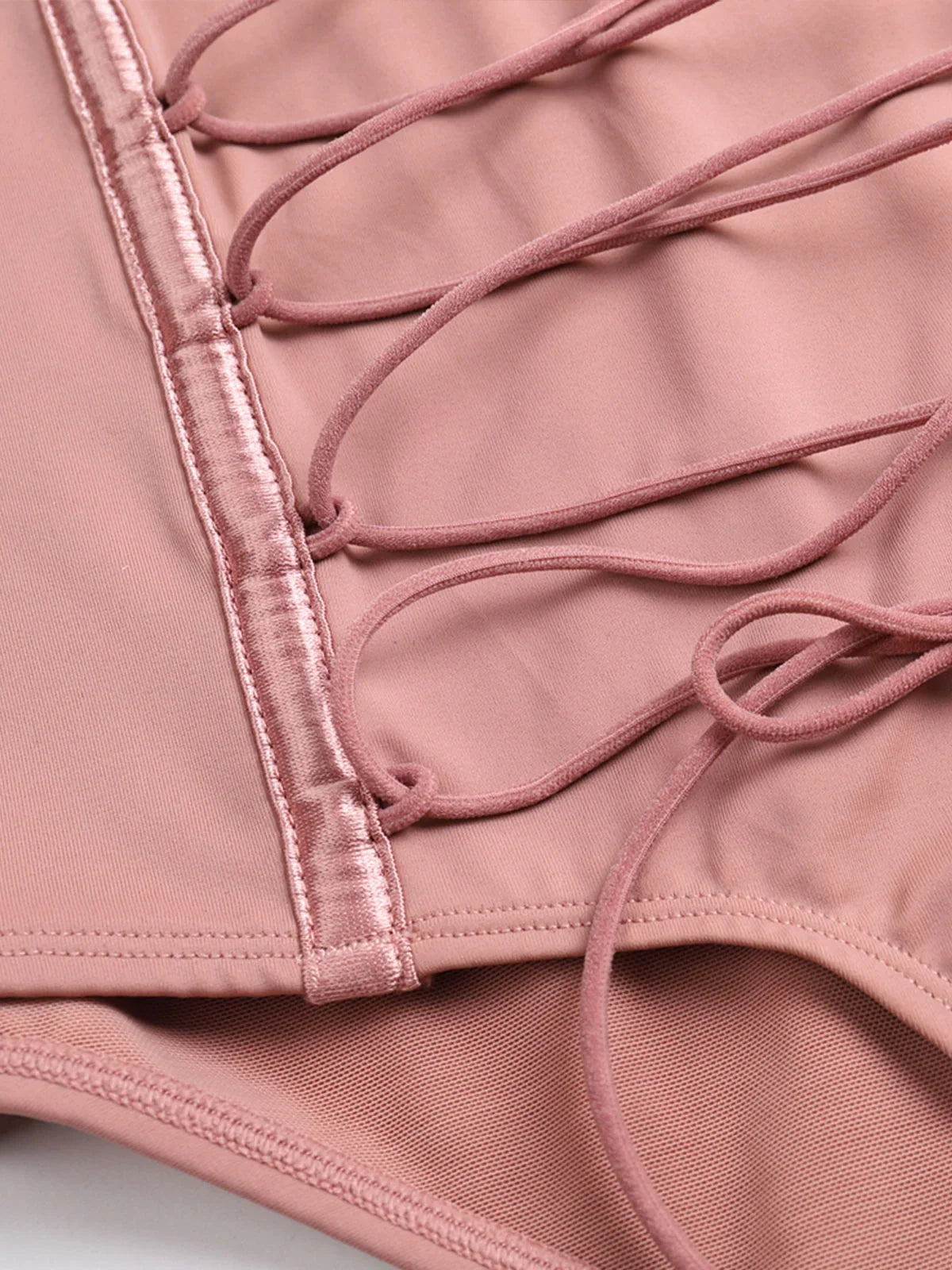 Close-up of blush pink Formivelle push-up corset bodysuit with satin trim and lace-up detail